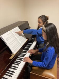 Two children playing an upright piano